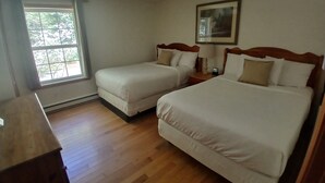 Ett hotellrum med två sängar, en takfläkt, ett fönster med utsikt och en inramad tavla på väggen.