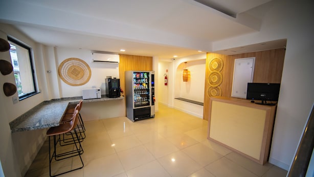 A modern kitchen with a bar area, a refrigerator, and a coffee machine. - Amazinn Hotel (Belém)