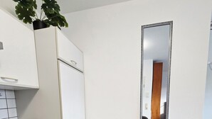 A modern kitchen with white cabinets, a kettle, a stove, and a radiator. - Apartment near the clinic (Idar-Oberstein)
