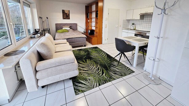 A compact living space with a bed, sofa, dining table, and kitchenette. - Apartment near the clinic (Idar-Oberstein)