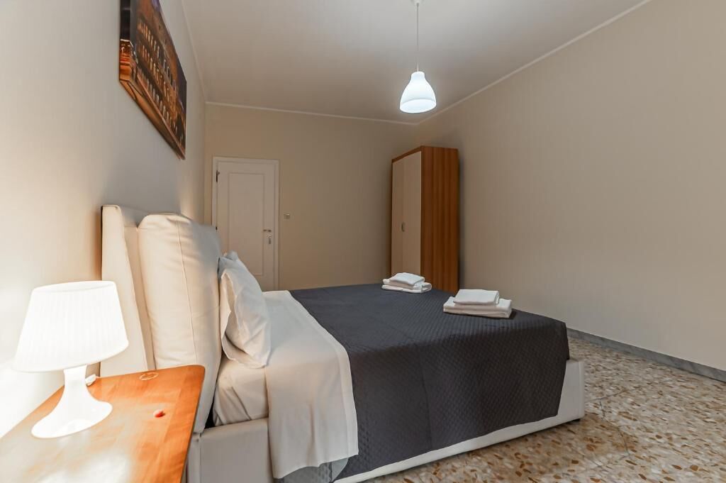 Un dormitorio con una cama, una mesita de noche, una lámpara, un armario y una puerta.