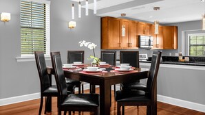 A dining area with a wooden table, black chairs, and a vase of flowers. - Enchanted Garden Townhouses  (Orlando)