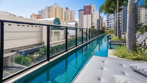 A rooftop pool with a city view, lounge chairs, and a glass railing. - Apts in a Condo. w/ Pool, a few Steps fr/ Vaca Brava Park - Obds (Goiânia)