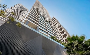 Un edificio moderno de gran altura con un diseño angular distintivo, que cuenta con múltiples balcones y fachada de vidrio.