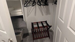 Un dressing avec des étagères, un banc et des vêtements suspendus.