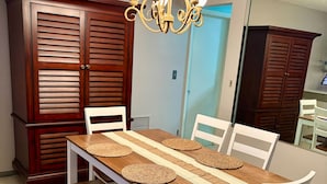 A dining area with a wooden table, white chairs, woven placemats, and a chandelier. - Clean Central Location 3-bedroom 2 Bath house Palm Harbor 1 Block to Starbucks (Palm Harbor)