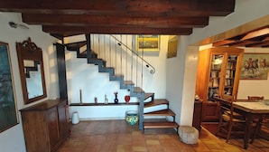 A staircase with a wooden finish, a bookcase, and a dining table with chairs.