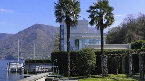 Une maison moderne avec une piscine, des palmiers et une montagne en arrière-plan.