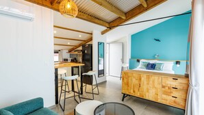 A modern room with a wooden ceiling, a blue accent wall, a bed with pillows, a wooden cabinet, and a glass table. - Loft with sea view, A/C and parking (Saint-Pierre)