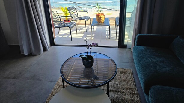 A room with a glass table, a sofa, and a view of the ocean through large windows. - Loft with sea view, A/C and parking (Saint-Pierre)