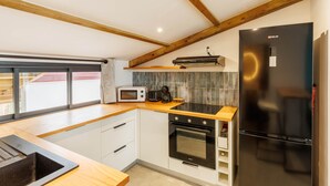 A modern kitchen with wooden beams, a black refrigerator, a microwave, a toaster, and a stove. - Loft with sea view, A/C and parking (Saint-Pierre)