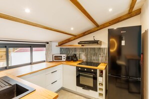 A modern kitchen with wooden beams, a black refrigerator, a microwave, a toaster, and a stove. - Loft with sea view, A/C and parking (Saint-Pierre)