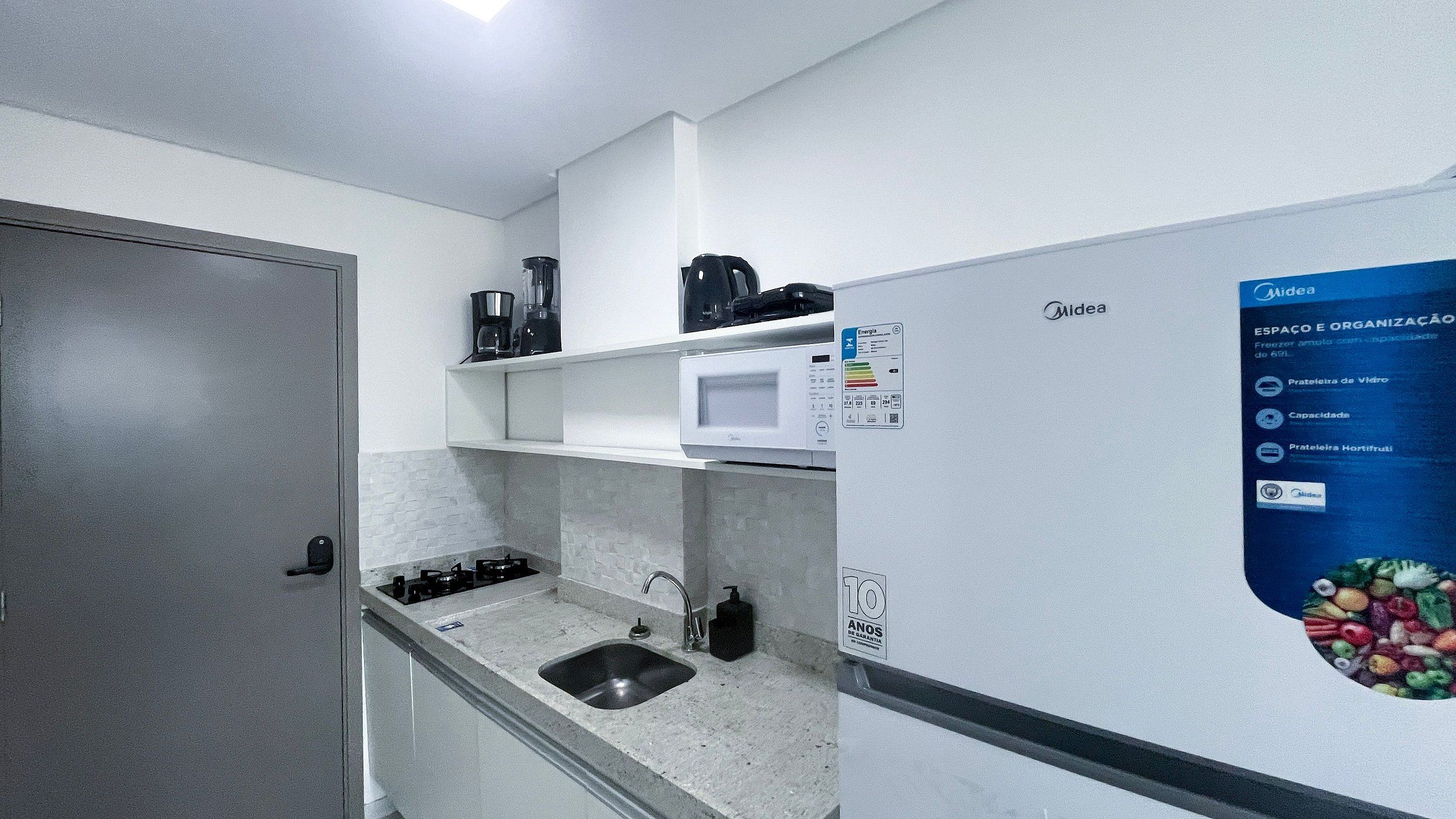 A compact kitchenette with a microwave, coffee maker, and a refrigerator.