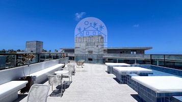Una terraza en la azotea con mobiliario exterior, piscina y vistas a la ciudad.