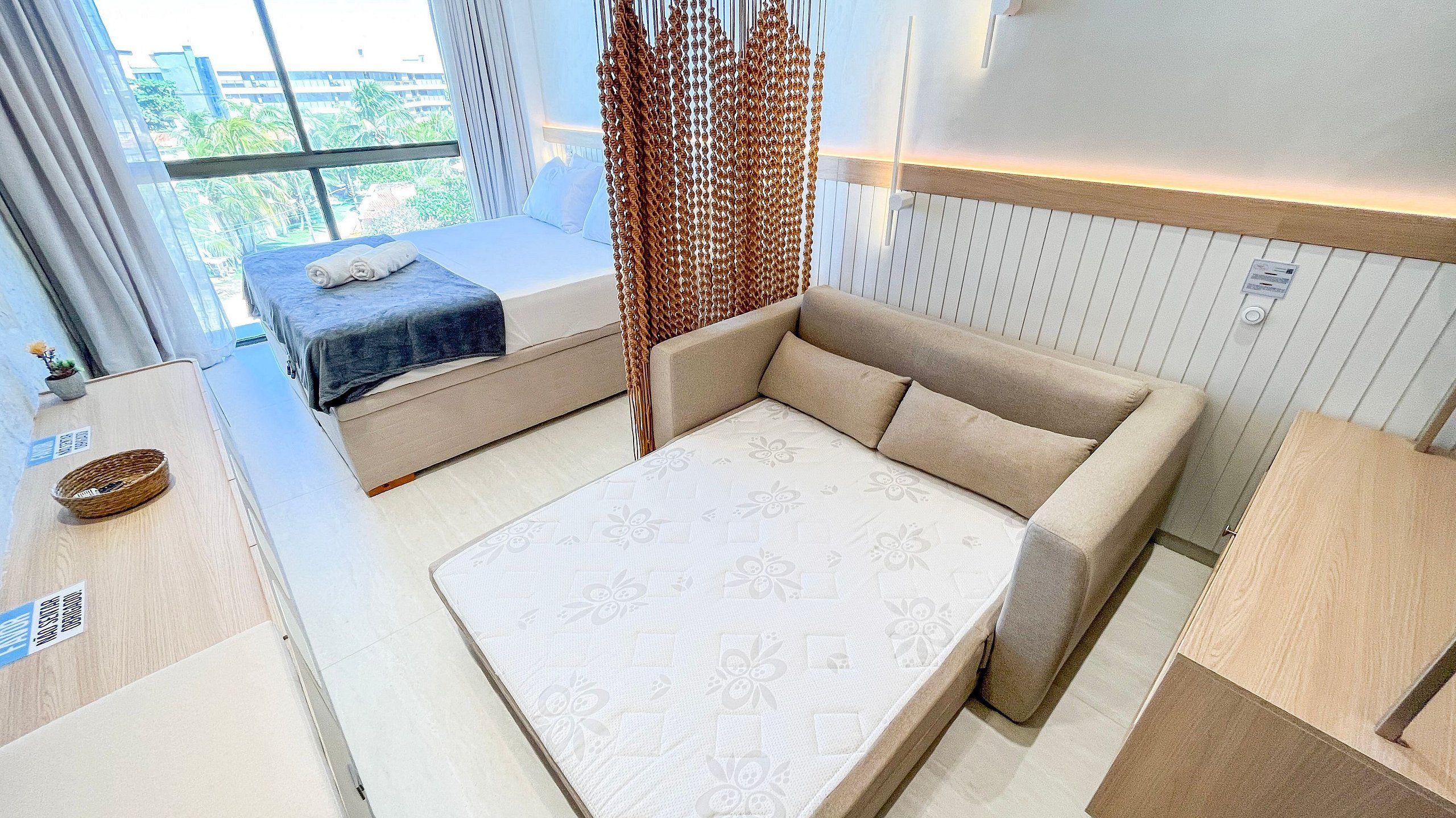 Une chambre moderne avec un lit, un canapé et une vue sur la verdure environnante.