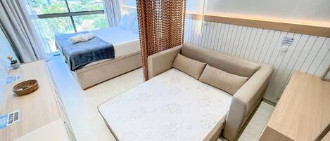 Une chambre moderne avec un lit, un canapé et une vue sur la verdure environnante.