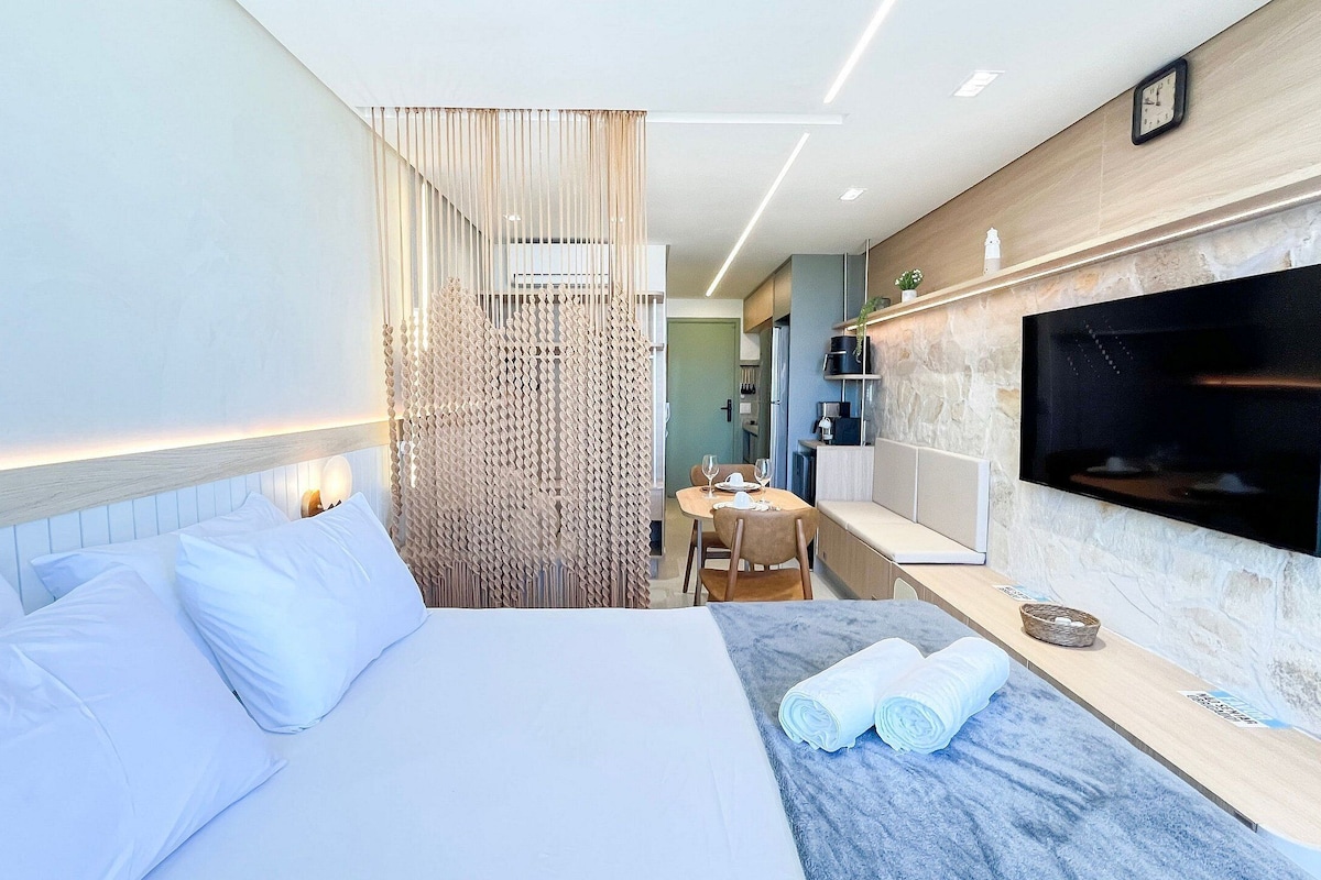 Una habitación de hotel moderna con cama, televisor, zona de comedor y baño.