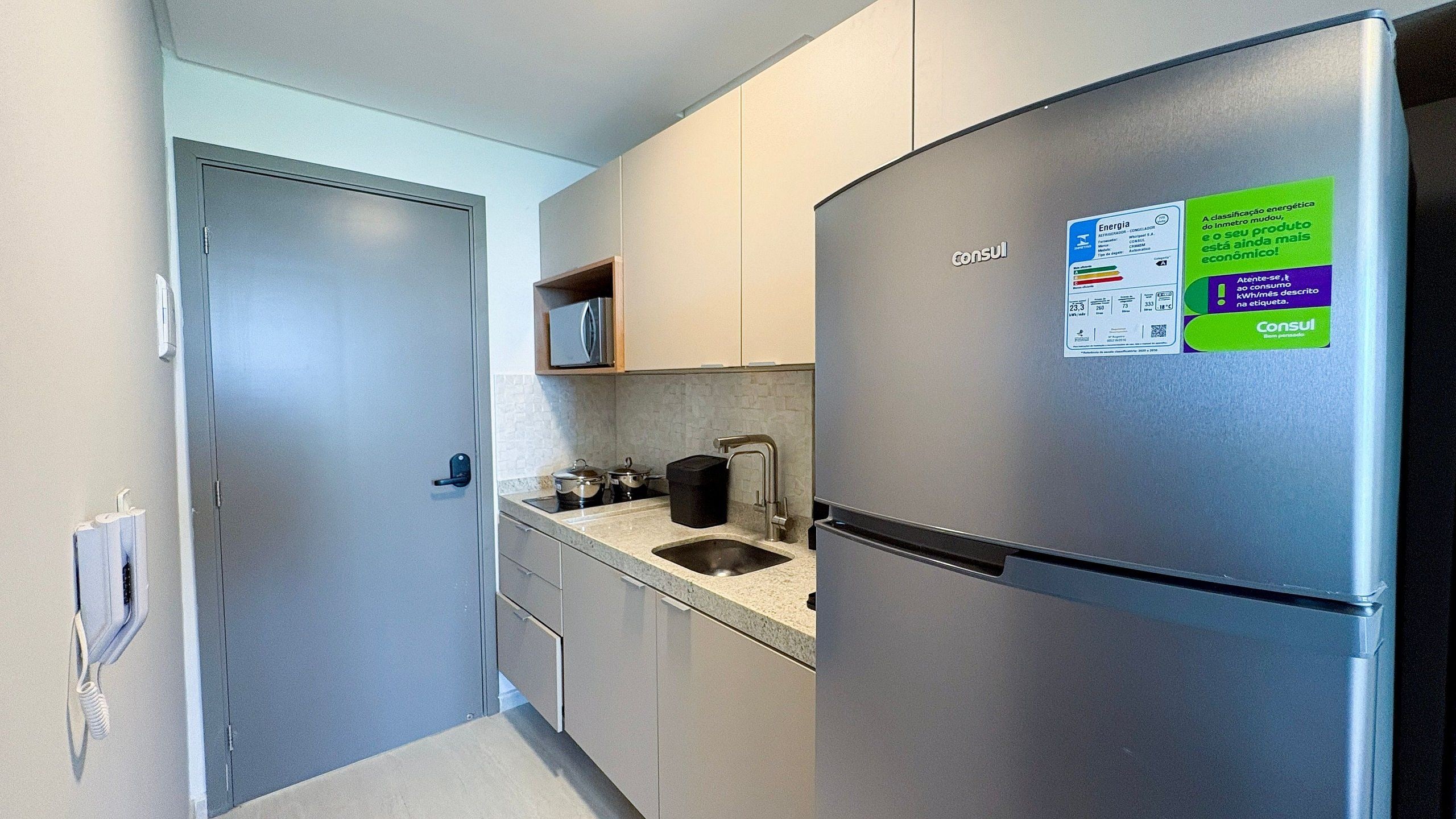 Una cucina compatta con frigorifero in acciaio inox, lavandino e forno a microonde.