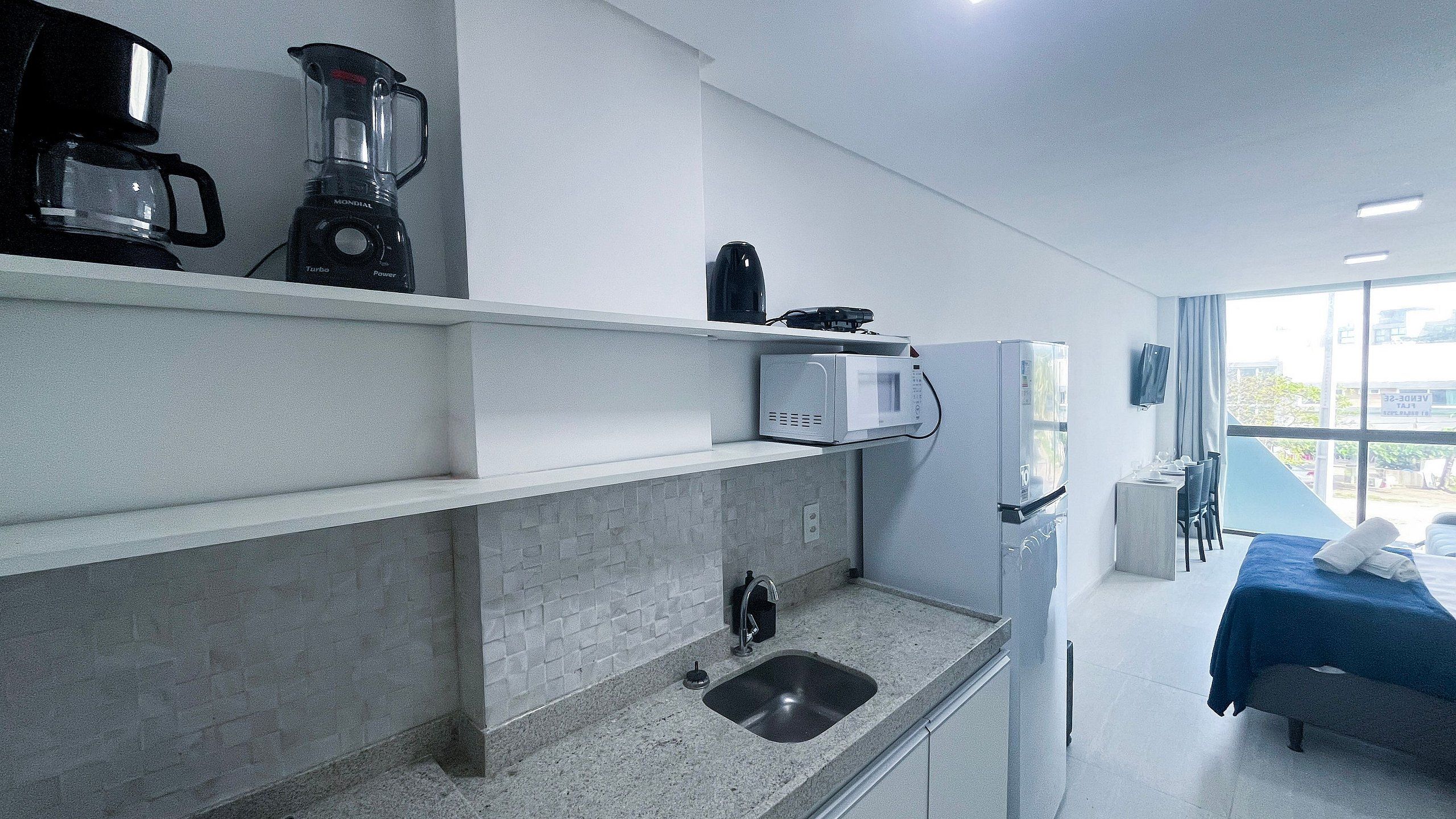 A modern kitchen with a built-in coffee maker, microwave, and sink.