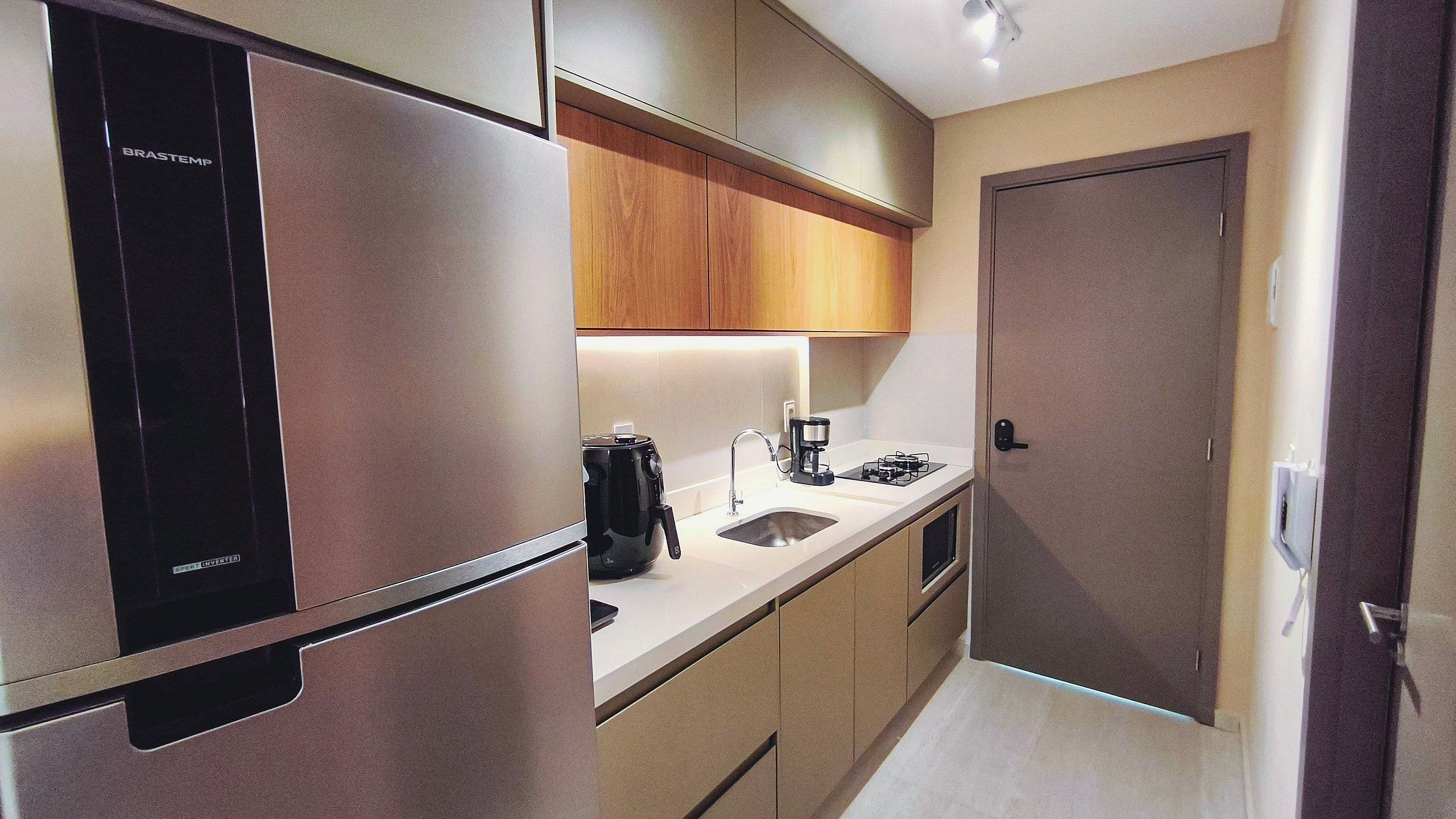 A compact kitchen with a refrigerator, coffee maker, and a stove.