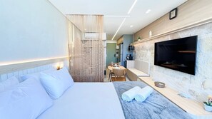 A modern hotel room with a bed, a TV, a dining area, and a bathroom. - Prime Beach Carneiros (Tamandaré)
