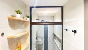 A modern bathroom with a glass shower enclosure, wooden shelves, and a small plant. - Prime Beach Carneiros (Tamandaré)