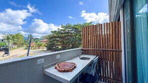 A balcony with a small sink and a wooden tray, overlooking a residential area with trees and a clear sky. - Prime Beach Carneiros (Tamandaré)