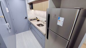 A compact kitchen with a stainless steel refrigerator, a gas stove, and a sink. - Prime Beach Carneiros (Tamandaré)