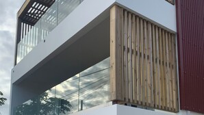 Un edifici modern de dos pisos amb un balcó, grans finestres i una paret vermella.