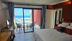 Habitació d'hotel amb llit, escriptori, ordinador, cadira i un balcó amb vista al mar.