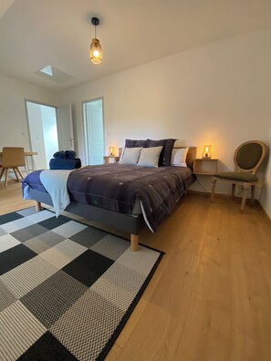 A bedroom with a bed, bedside lamps, a chair, a desk, and a view of the outside. - Cottage "La Mancellière" (Baguer-Pican)