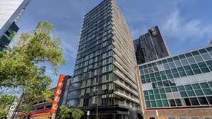 A modern high-rise building with a glass facade, surrounded by other contemporary structures. - Modern High-Rise Condo | 2 Bed | 1 Bath | (Winnipeg)