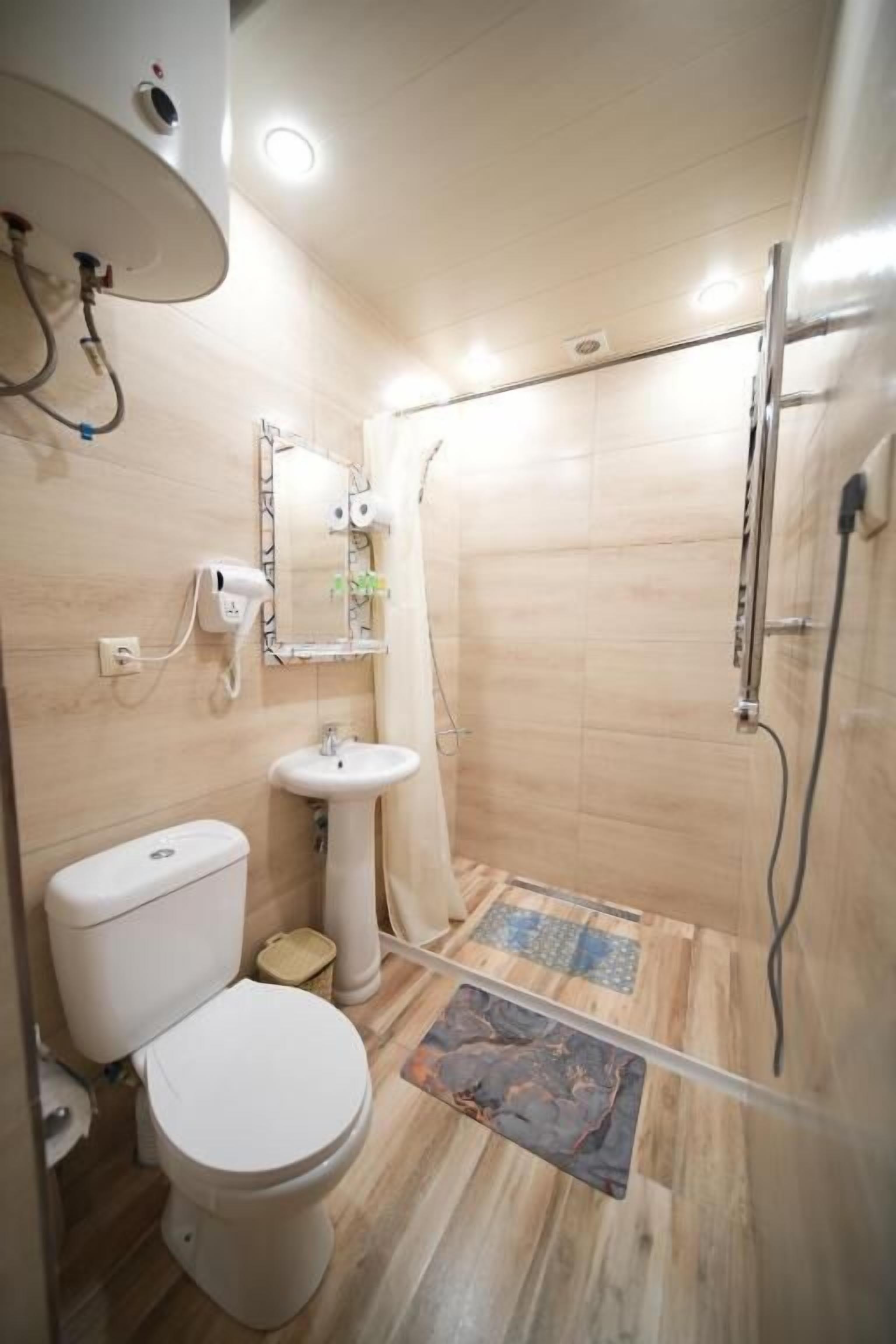 A bathroom with a toilet, sink, shower, and a mirror.