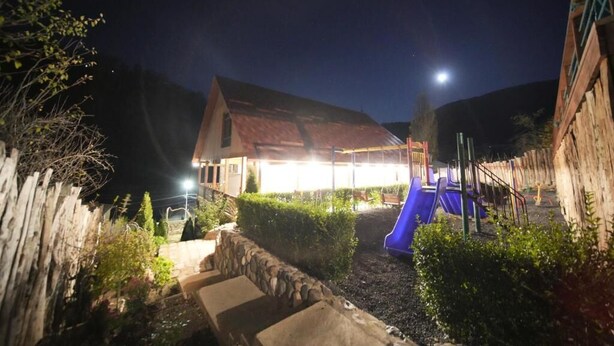 A house with a red roof, a blue slide, and a stone wall. - Maru house (Dilijan)