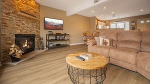 Una sala de estar con chimenea, un sofá, una mesa de centro y un televisor.