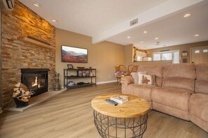 A living room with a fireplace, a sofa, a coffee table, and a television. - “Happy Place” Walk to Wisp, Hot Tub, Lake Access (McHenry)