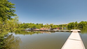Un lago tranquilo con un muelle que se adentra en el agua, rodeado de abundante vegetación.