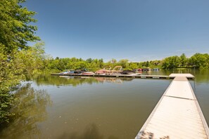 A calm lake with a dock extending into the water, surrounded by lush greenery. - “Happy Place” Walk to Wisp, Hot Tub, Lake Access (McHenry)