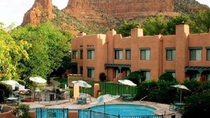 Un hotel con piscina, area salotto esterna e montagne sullo sfondo.