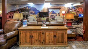 Una hall con divani in pelle, un armadio in legno, una televisione e un murale raffigurante un paesaggio desertico.