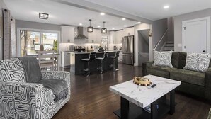 A modern kitchen with white cabinets, stainless steel appliances, and a central island with bar stools. - 5 Bedrooms w. TVs in every room & Garage Parking (Overland Park)