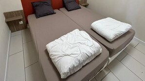 A double bed with a red headboard, two pillows, and a white blanket. - 2-bedroom apartment with private pool (Saint-Paul)