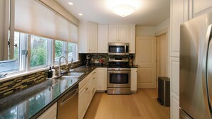 A modern kitchen with a stainless steel refrigerator, double ovens, a microwave, and a sink with a window above. - Harborside Grand Haven - Walk to Lake Michigan (Grand Haven)