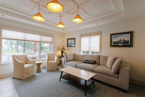 A living room with a sofa, two armchairs, a coffee table, and three hanging lamps.