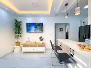 A modern kitchen with a marble countertop, a built-in refrigerator, and pendant lighting.