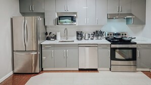 A modern kitchen with stainless steel appliances, grey cabinets, and a white countertop. - Element / King Bed / Elevator / Adjustable Desk (Philadelphia)