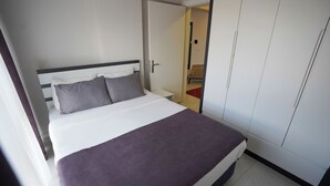 Ein Bett mit weißem Kopfteil, zwei Kissen und einer violetten Decke.