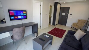 Ein modernes Wohnzimmer mit Flachbildfernseher, grauem Sofa, grauem Sessel und Couchtisch.