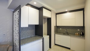 Eine moderne Küche mit weißen Schränken, einer Granitabdeckung, einer integrierten Spüle und einem Kühlschrank.