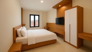 Una habitación de hotel moderna con una cama, un televisor montado en la pared, un armario de madera y una ventana con vistas a la ciudad.